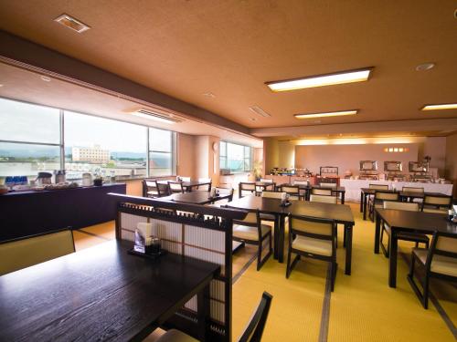 a restaurant with tables and chairs and a large window at hotel miura kaen in Takikawa