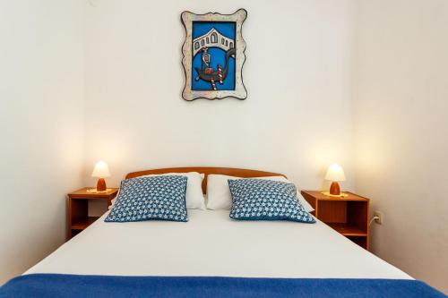 a bedroom with a bed with blue and white pillows at Apartment Baldigara in Njivice