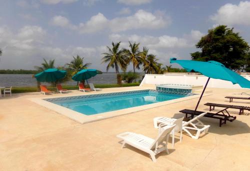 a swimming pool with chairs and umbrellas next to a swimming pool at Hôtel Katakalousse in Yembakana
