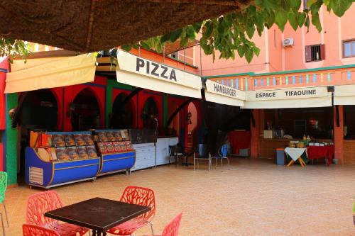 a market with a table and chairs in front of a building at Hotel Espace Tifawine in Tafraoute