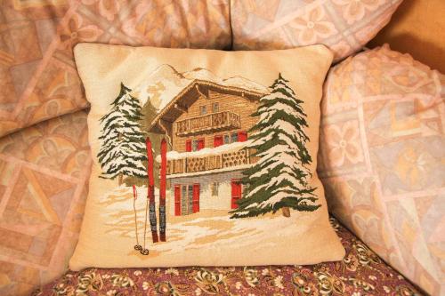 a pillow with a picture of a house in the snow at Hotel Les Saisons in Saint Vincent