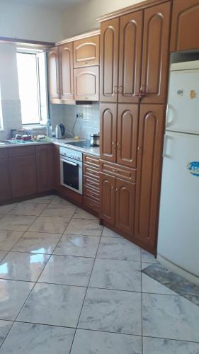 a kitchen with wooden cabinets and a white refrigerator at Olympic View Guesthouse in Kalami