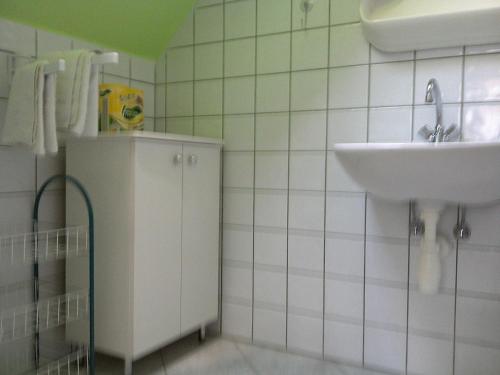 a bathroom with a sink and a white tiled wall at Akácfa Hortenzia Apartman in Zalakaros