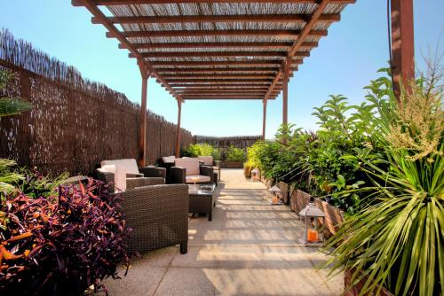 a patio with chairs and plants and a wooden pergola at Ibis Granada in Granada