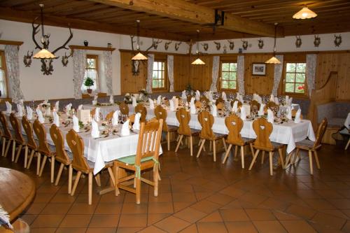 um salão de banquetes com mesas e cadeiras brancas em Bioalm Wassermann Wirt em Sommereben