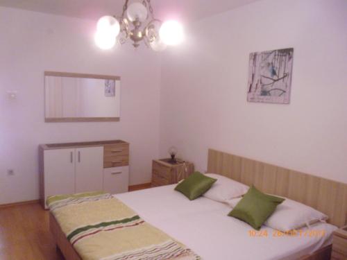 a bedroom with a bed with two green pillows at Apartments Lidija in Pag