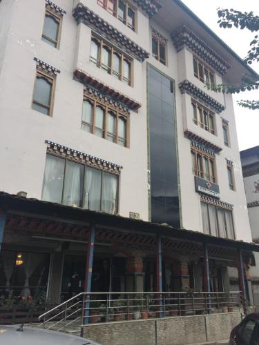 a tall white building with windows on a street at Khamsum Inn in Thimphu
