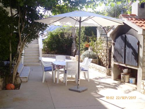 a table and chairs under an umbrella on a patio at Apartments Lidija in Pag