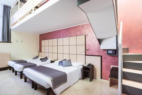 a group of four beds in a room at Ibis Styles Milano Centro in Milan