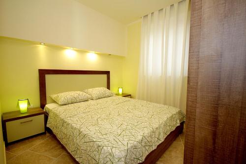a bedroom with a bed and two night stands with lamps at Apartments Oktopus in Sutomore