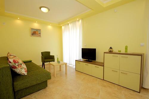 a living room with a couch and a flat screen tv at Apartments Oktopus in Sutomore