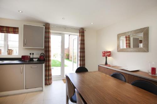 a kitchen with a table and a dining room at DBS Serviced Apartments - The Stretton in Castle Donington