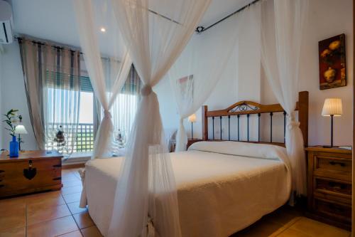 um quarto com uma cama com cortinas brancas em Apartamento Levante em Conil de la Frontera