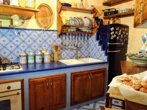 a kitchen with a sink and a blue tiled wall at L’altra Sicilia…da Amare in Acquedolci