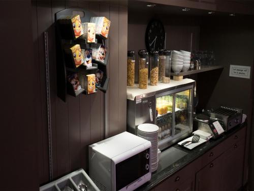 a kitchen with a microwave and a counter with food at Hotel Orchidee in Aalter
