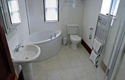 a bathroom with a tub and a sink and a toilet at Stocks Hotel in Sark
