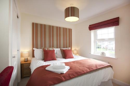 a bedroom with a large bed with a red blanket at DBS Serviced Apartments - The Stretton in Castle Donington