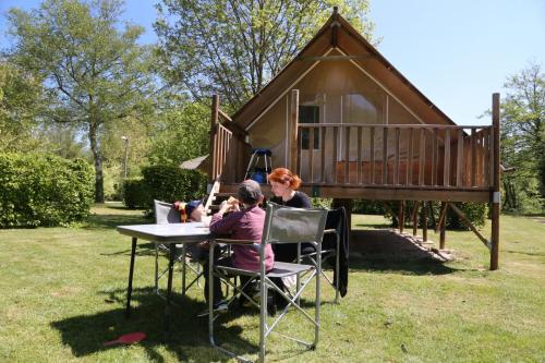 two people sitting at a table in front of a cabin at Camping le Nid du Parc in Villars-les-Dombes