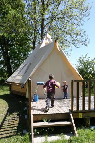 two children are standing inside of a tent at Camping le Nid du Parc in Villars-les-Dombes