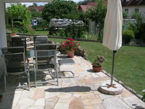 a patio with chairs and an umbrella and a table at Ferienwohnung Familie Sinn in Pappenheim