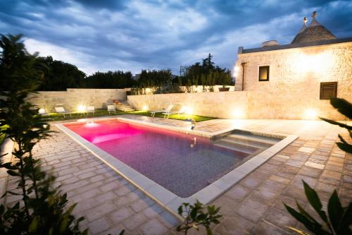 a swimming pool in the middle of a yard at night at Trulli Magravì - Apparthotel in Alberobello