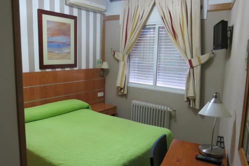 a bedroom with a green bed and a window at Hostal Don Juan I in Alcalá de Henares