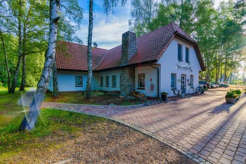 ein weißes Haus mit einem roten Dach und einer Auffahrt in der Unterkunft Seehotel Schorfheide in Althüttendorf