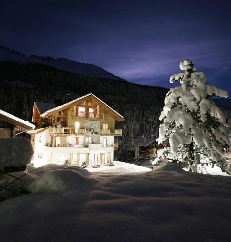 a ski lodge with a snow covered tree in front of it at Hotel Vedig in Santa Caterina Valfurva