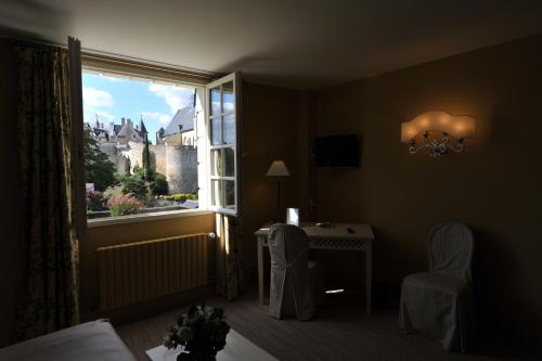 a bedroom with a window and a table and a chair at Hotel Spa Le Relais Du Bellay in Montreuil-Bellay