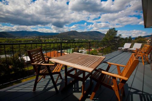 a wooden table and chairs on a balcony with mountains at New Norfolk Holiday Apartments in New Norfolk
