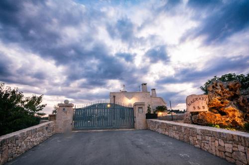 a gate in front of a house with a cloudy sky at Trulli Magravì - Apparthotel in Alberobello