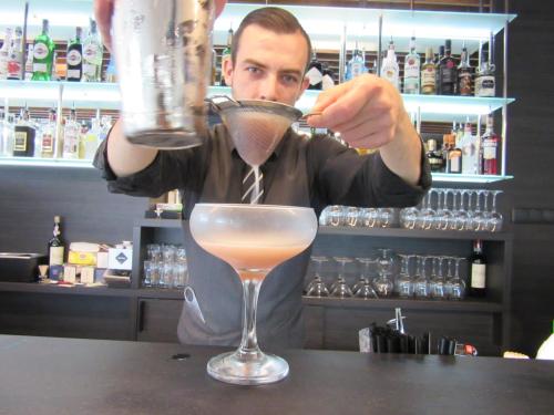 a man pouring a drink into a martini glass at Armada Holiday House in Dziwnów