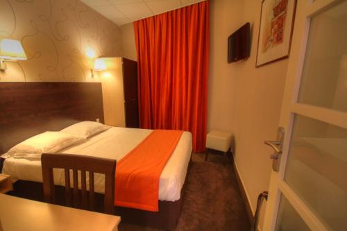 Habitación de hotel con cama y cortina roja en Hôtel Des Trois Gares, en París