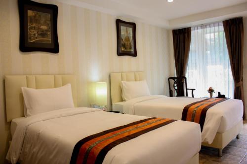 a hotel room with two beds and a window at Chuchaiburi Sri Amphawa in Amphawa