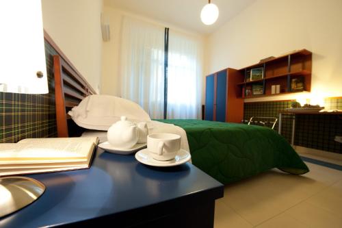 a room with a bed and a table with cups and saucers at Hotel Villa Sturzo in Caltagirone
