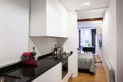 una cocina con armarios blancos y un aparato rojo en una encimera en Baps Apartaments 2, en Bilbao