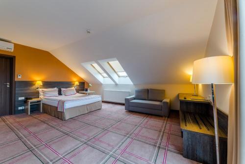 a bedroom with a bed and a couch in a room at Mikołajki Resort Hotel & Spa Jora Wielka in Mikołajki