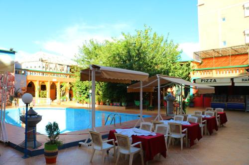 ein Restaurant mit Tischen und Stühlen neben einem Pool in der Unterkunft Hotel Espace Tifawine in Tafraout