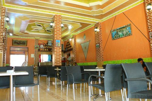 a dining room with tables and chairs and orange walls at Hotel Espace Tifawine in Tafraoute