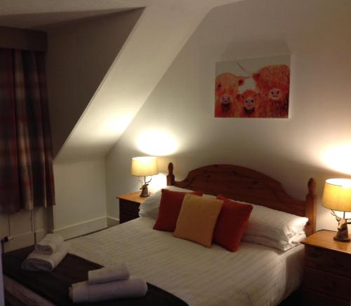 a bedroom with a bed with two lamps and a painting at Abbey Guest House in Peterhead