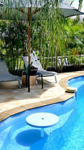 a pool with two chairs and a table next to it at Le Kerveguen in Saint-Gilles les Bains