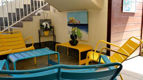 a room with yellow and blue chairs and a staircase at Le Kerveguen in Saint-Gilles les Bains