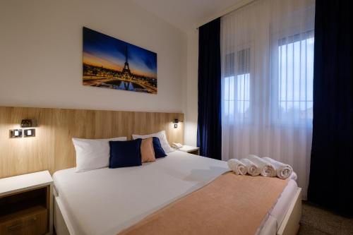 a bedroom with a large white bed and a window at Airport Hotel Garni in Belgrade