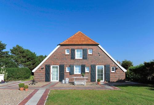 a brick house with a bench in front of it at Landhaus Meer in Neuharlingersiel