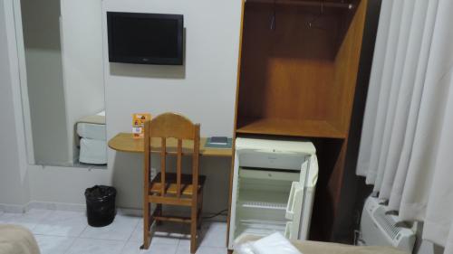 a small room with a small desk and a tv at Presidente Hotel in Passos