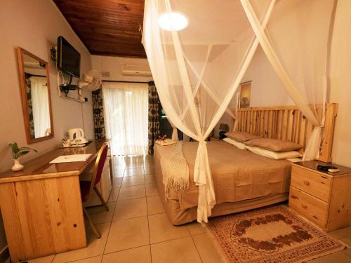 um quarto com uma cama de dossel, uma secretária e um lavatório. em Palmwood Lodge em Lusaka