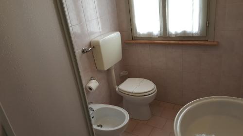 a bathroom with a toilet and a sink and a window at Hotel Sporting in Campagnola Emilia