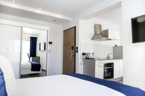 a white bedroom with a bed and a kitchen at Pebbles Boutique Aparthotel in Sliema