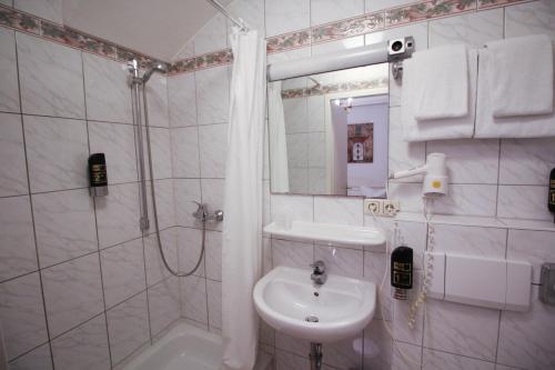 a white bathroom with a sink and a shower at Hotel Seibel in Munich