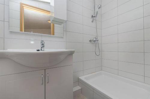 a white bathroom with a sink and a tub at Apartment Neda in Duće